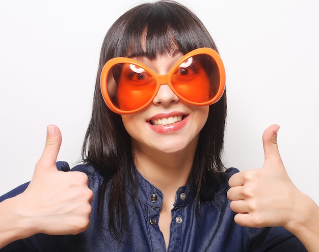 Jonge gelukkige vrouw met grote oranje zonnebril