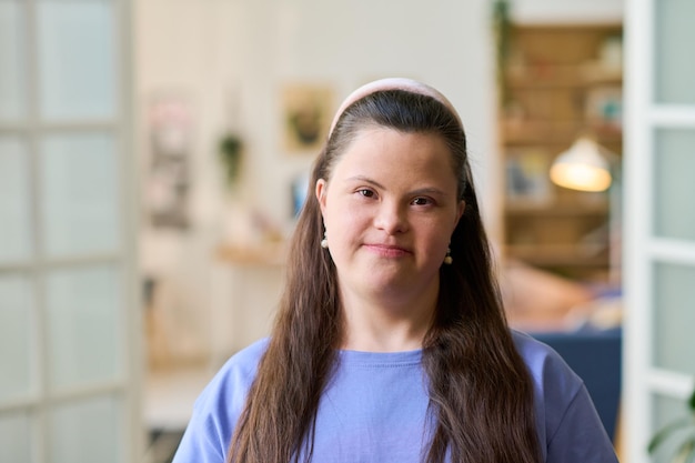 Jonge gelukkige vrouw met het syndroom van down die thuis voor de camera staat