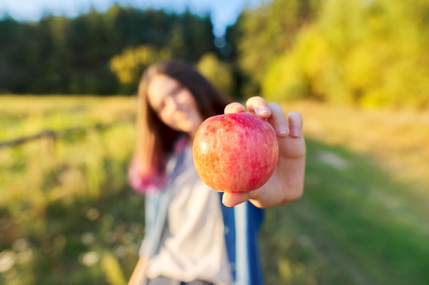 Jonge gelukkige vrouw met rode appel, meisje dat een appel bijt, zonsondergang natuurlijke landschapsachtergrond, gezonde natuurlijke voeding