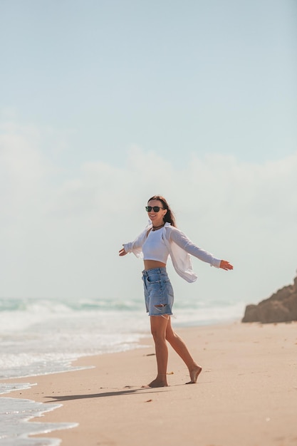 Jonge gelukkige vrouw op het strand geniet van haar zomervakantie Meisje is gelukkig en kalm tijdens haar verblijf op het strand