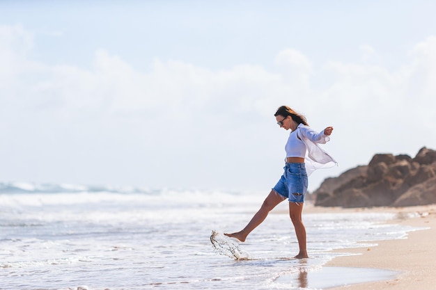 Jonge gelukkige vrouw op het strand geniet van haar zomervakantie Meisje is gelukkig en kalm tijdens haar verblijf op het strand