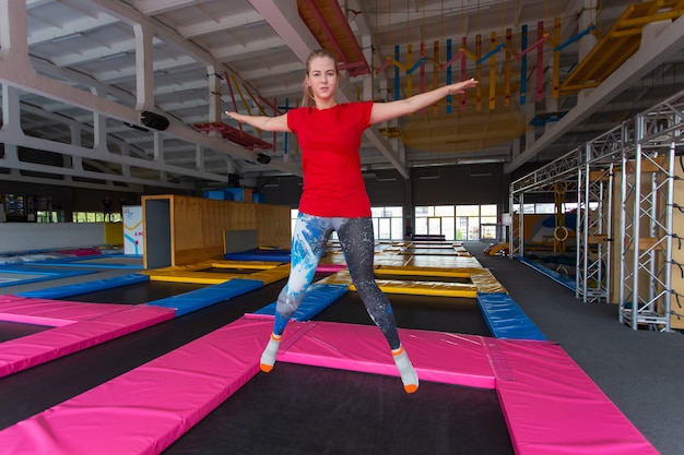 Jonge gelukkige vrouw springen op een trampoline binnenshuis.