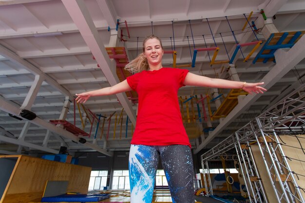 Jonge gelukkige vrouw springen op een trampoline binnenshuis.