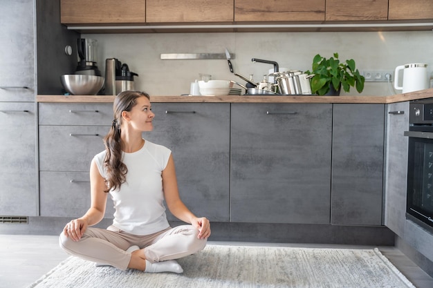 Jonge gelukkige vrouw zit op een achtergrond van vuile afwas in de keuken Slowdown zelfzorg slow life concept