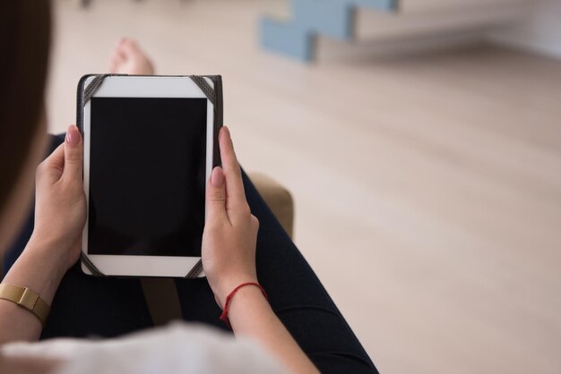 jonge gelukkige vrouw zittend op de bank met tabletcomputer in luxe huis