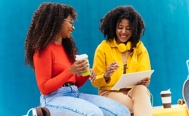 Jonge gelukkige vrouwen die op een tablet-apparaat studeren