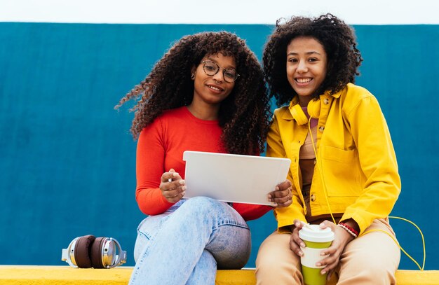 Jonge gelukkige vrouwen die op een tablet-apparaat studeren