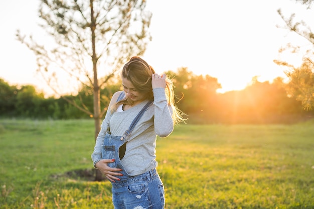 Jonge gelukkige zwangere vrouw ontspannen en genieten van het leven in de natuur