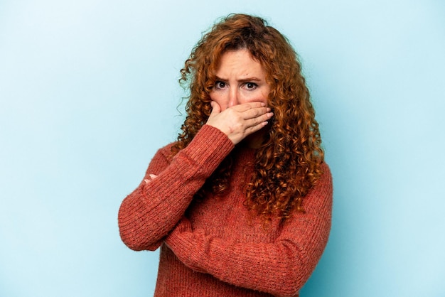 Foto jonge gember blanke vrouw geïsoleerd op blauwe achtergrond bang en bang