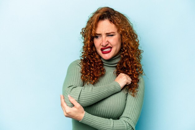 Jonge gember blanke vrouw geïsoleerd op blauwe achtergrond masseren elleboog lijden na een slechte beweging