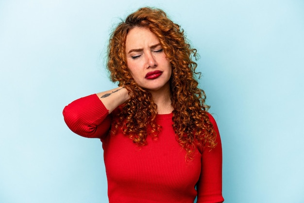 Jonge gember blanke vrouw geïsoleerd op blauwe achtergrond met nekpijn als gevolg van stress, masseren en aanraken met de hand