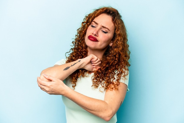 Jonge gember blanke vrouw geïsoleerd op blauwe achtergrond met nekpijn als gevolg van stress, masseren en aanraken met de hand