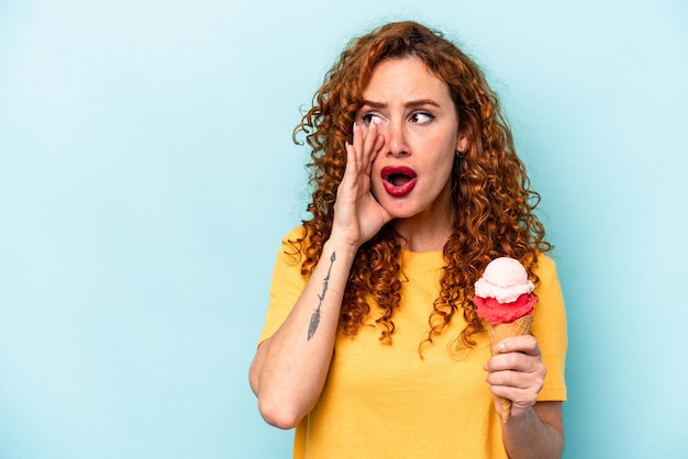 Jonge gembervrouw met een ijsje geïsoleerd op een blauwe achtergrond die de achterkant van het hoofd aanraakt en een keuze maakt