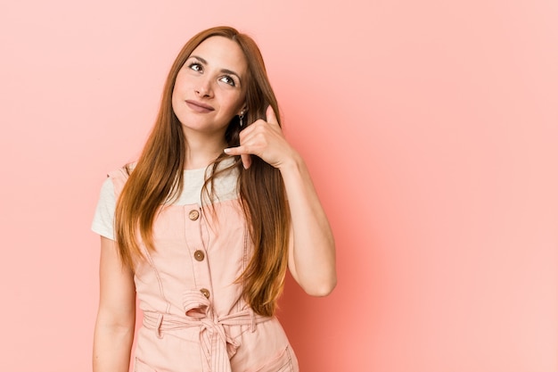 Jonge gembervrouw met sproeten die een mobiel telefoongesprekgebaar met vingers tonen.