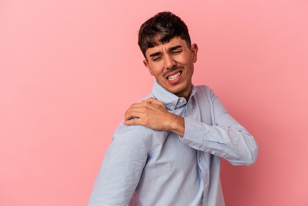 Jonge gemengd ras man geïsoleerd op roze achtergrond met pijn in de schouder.