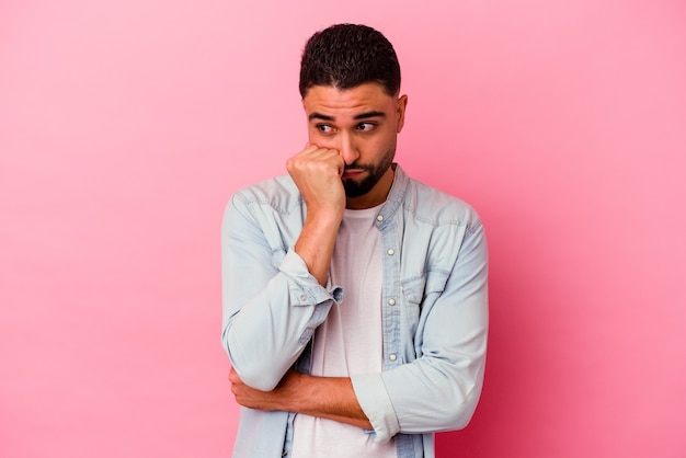 Jonge gemengd ras man geïsoleerd op roze nagels bijten, nerveus en erg angstig.