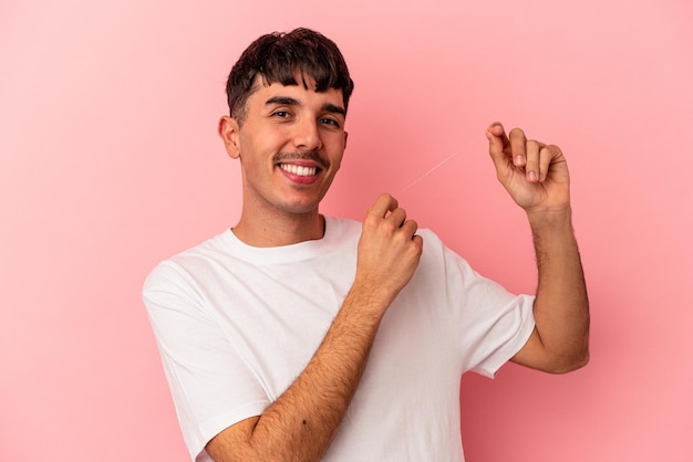 Jonge gemengd ras man met een floss geïsoleerd op roze background