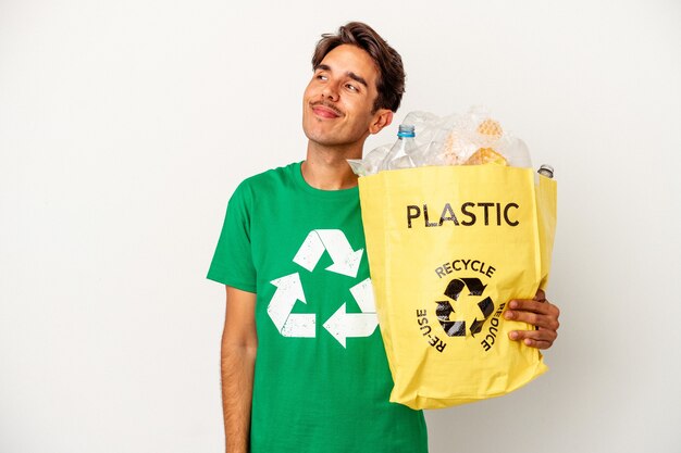 Jonge gemengd ras man recycling van plastic geïsoleerd op gele achtergrond dromen van het bereiken van doelen en doeleinden