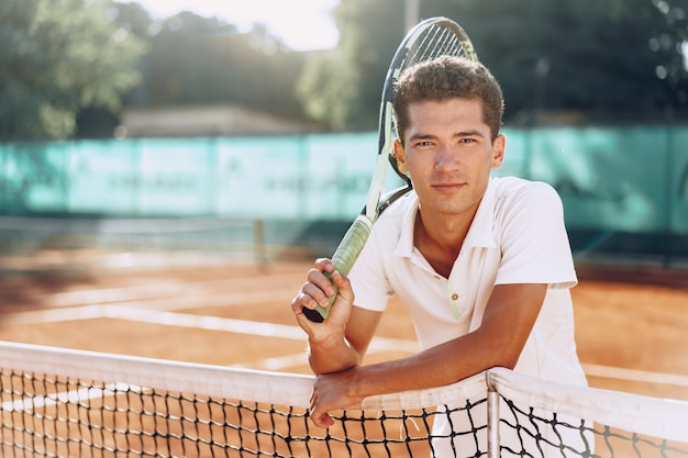 Jonge gemengd ras man tennisser met racket staande op de tennisbaan