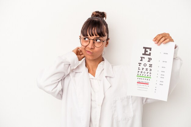 Jonge gemengd ras opticien vrouw doet een test geïsoleerd op een witte achtergrond achterhoofd aanraken, denken en een keuze maken.