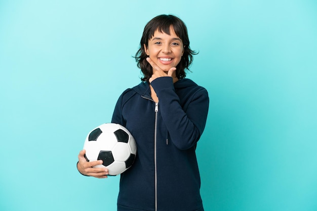 Jonge gemengd ras voetballer vrouw geïsoleerd op blauwe achtergrond gelukkig en lachend