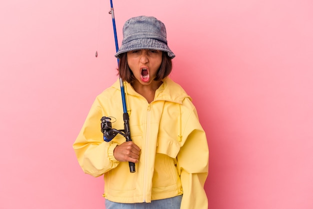 Jonge gemengd ras vrouw beoefenen van vissen geïsoleerd op roze achtergrond schreeuwen erg boos en agressief.