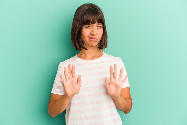 Jonge gemengd ras vrouw geïsoleerd op blauwe achtergrond lachen om iets, mond bedekken met handen.