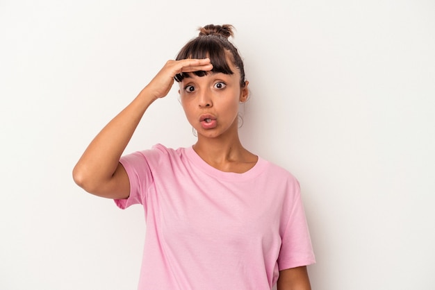 Jonge gemengd ras vrouw geïsoleerd op een witte achtergrond op zoek ver weg houden hand op het voorhoofd.