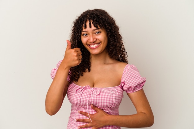 Jonge gemengd ras vrouw geïsoleerd op een witte achtergrond raakt buik, glimlacht zachtjes, eten en tevredenheid concept.