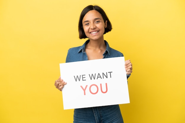 Jonge gemengd ras vrouw geïsoleerd op gele achtergrond houden We Want You board met gelukkige uitdrukking