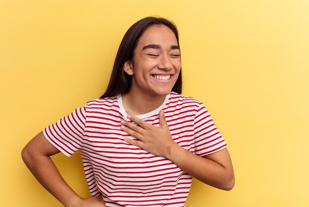 Jonge gemengd ras vrouw geïsoleerd op gele achtergrond lachen houden handen op het hart, concept van geluk.