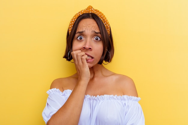 Jonge gemengd ras vrouw geïsoleerd op gele achtergrond vingernagels bijten, nerveus en erg angstig.