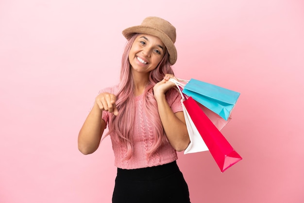 Jonge gemengd ras vrouw met boodschappentas geïsoleerd op roze achtergrond wijzend naar voren met gelukkige expression