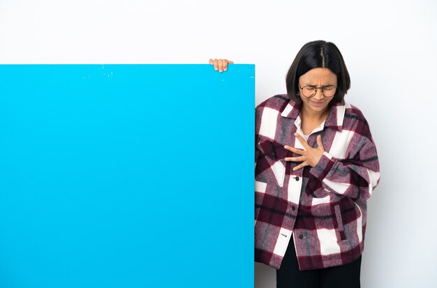 Jonge gemengd ras vrouw met een groot blauw bordje geïsoleerd op een witte achtergrond met pijn in het hart