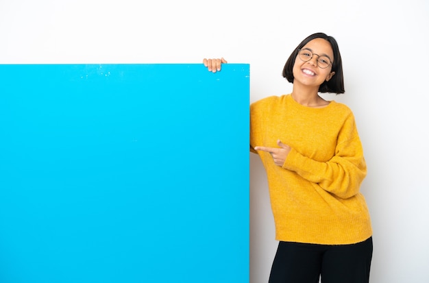 Jonge gemengd ras vrouw met een groot blauw bordje geïsoleerd op een witte achtergrond wijzende vinger naar de zijkant