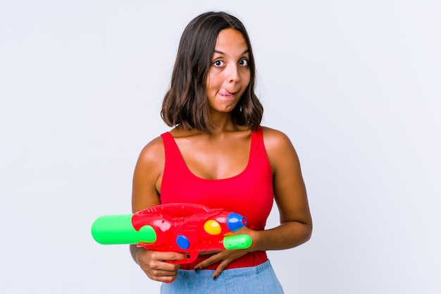 Jonge gemengd ras vrouw met een waterpistool geïsoleerd raakt buik, glimlacht zachtjes, eten en tevredenheid concept.