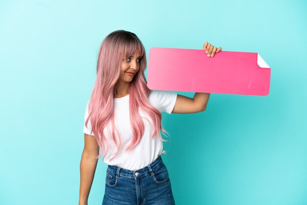 Jonge gemengd ras vrouw met roze haar geïsoleerd op blauwe achtergrond met een leeg bordje