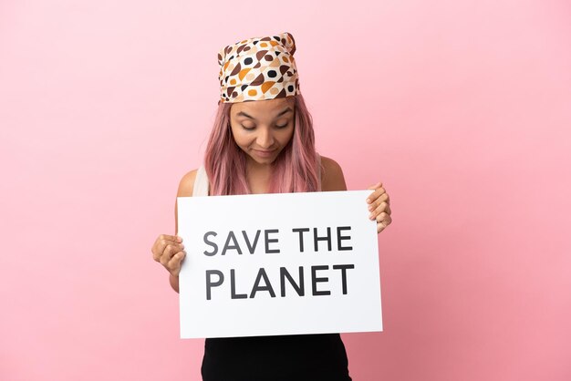 Jonge gemengd ras vrouw met roze haar geïsoleerd op roze achtergrond met een bordje met de tekst Save the Planet