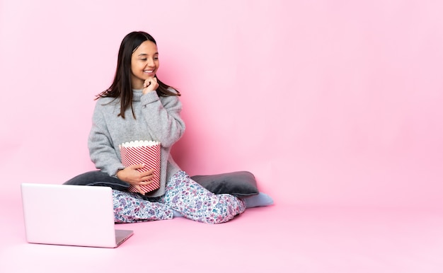 Foto jonge gemengd ras vrouw popcorn eten tijdens het kijken naar een film