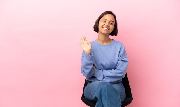 Jonge gemengd ras vrouw zittend op een stoel geïsoleerd