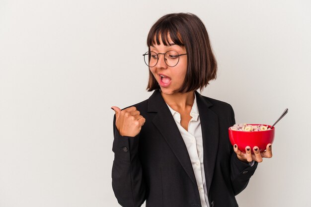 Jonge gemengd ras zakenvrouw eten granen geïsoleerd op een witte achtergrond punten met duim vinger weg, lachen en zorgeloos.