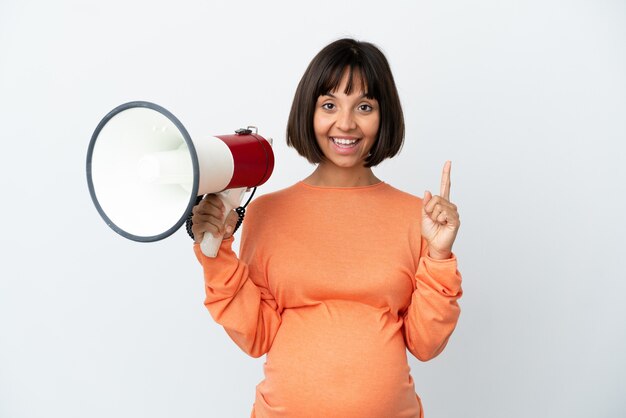 Jonge gemengd ras zwangere vrouw geïsoleerd op een witte achtergrond die een megafoon vasthoudt en een geweldig idee naar boven wijst