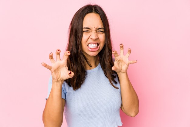 Jonge gemengde geïsoleerde ras Spaanse vrouw die klauwen toont die een kat, agressief gebaar imiteren.