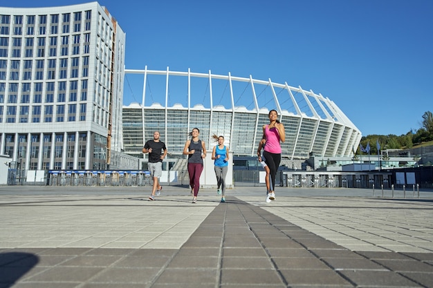 Jonge gemengde raciale atleten die op stadionachtergrond lopen