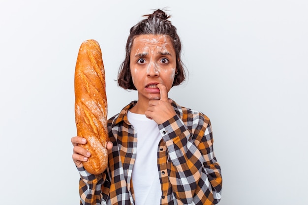 Jonge gemengde rasvrouw die brood maakt dat op witte achtergrond wordt geïsoleerd die vingernagels bijt, zenuwachtig en zeer angstig.