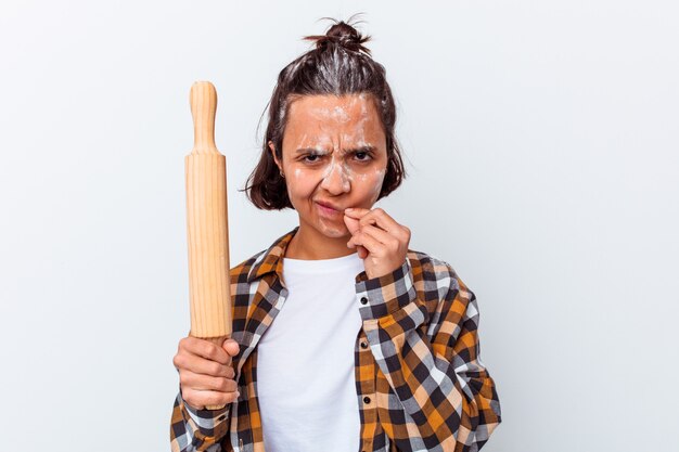 Jonge gemengde rasvrouw die brood maken dat op witte muur met vingers op lippen wordt geïsoleerd die een geheim houden.