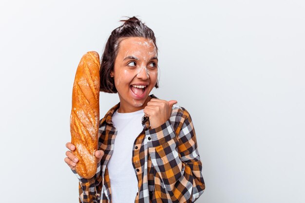 Jonge gemengde rasvrouw die brood maken dat op witte muurpunten met weg duimvinger wordt geïsoleerd, lachend en zorgeloos.