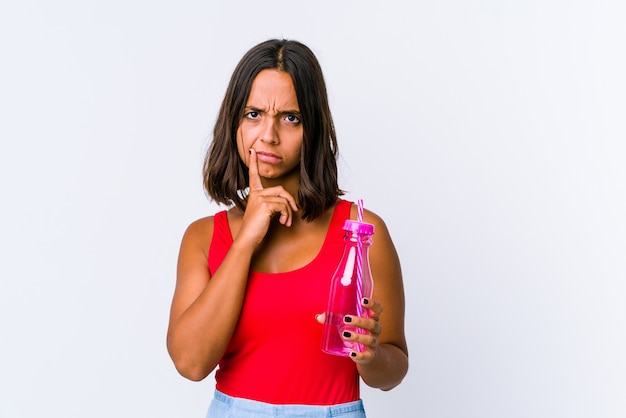 Jonge gemengde rasvrouw die een geïsoleerde milkshake houden overweegt, een strategie plant, nadenkt over de manier van een bedrijf.