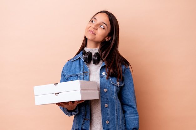 Jonge gemengde rasvrouw die een geïsoleerde pizza houdt die droomt van het bereiken van doelen en doeleinden