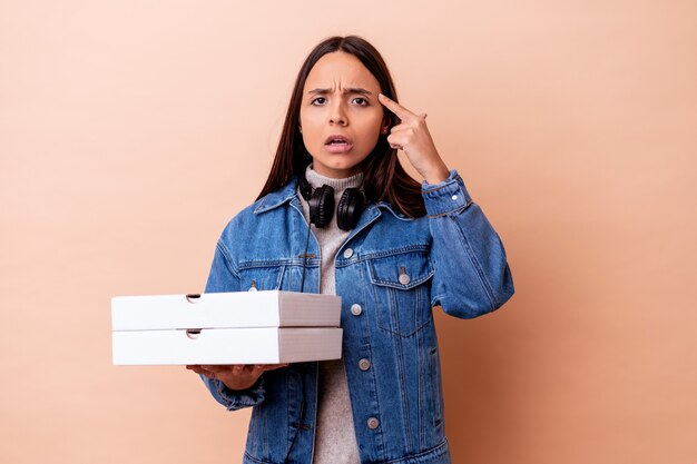 Jonge gemengde rasvrouw die een geïsoleerde pizza houdt die een teleurstellinggebaar met wijsvinger toont.